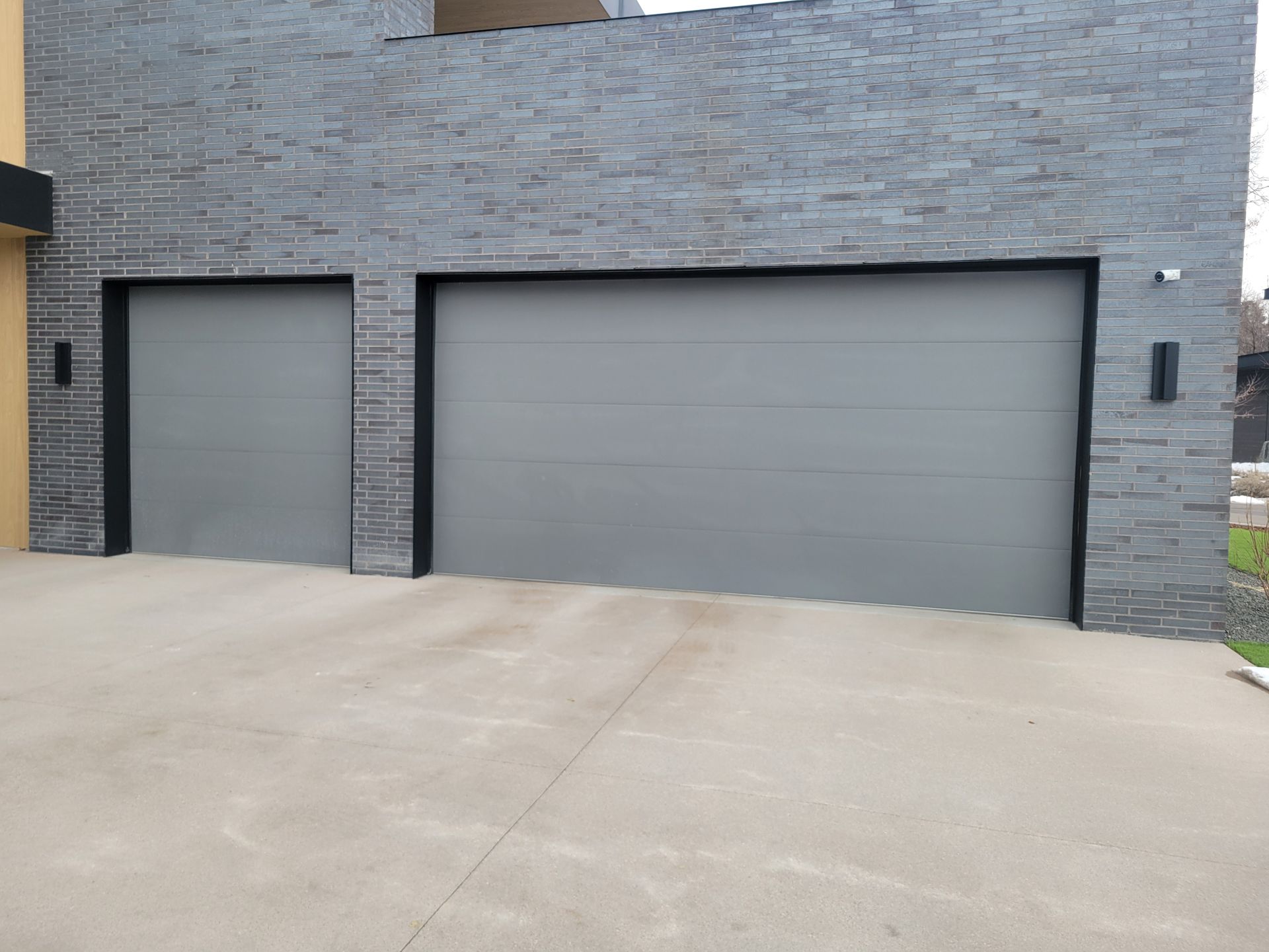 A modern house exterior featuring a two-car garage with two gray doors set into a gray stone facade.