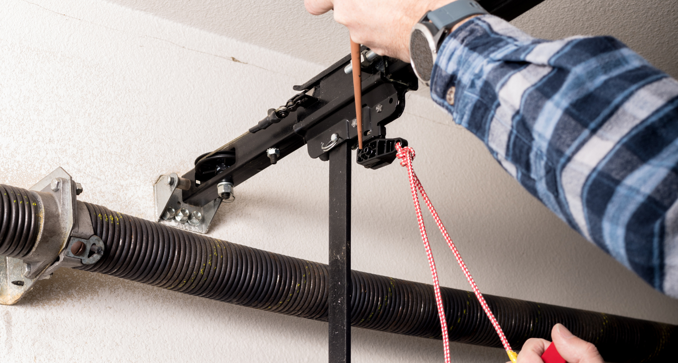 A person pulls the red emergency release cord on a garage door opener mechanism.