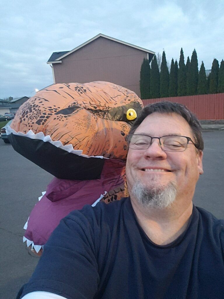 A man is taking a selfie with an inflatable dinosaur costume.