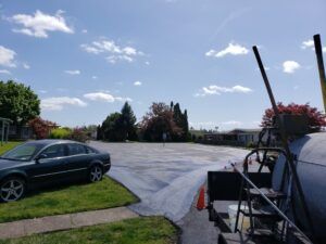 A car is parked in a driveway next to a concrete mixer.