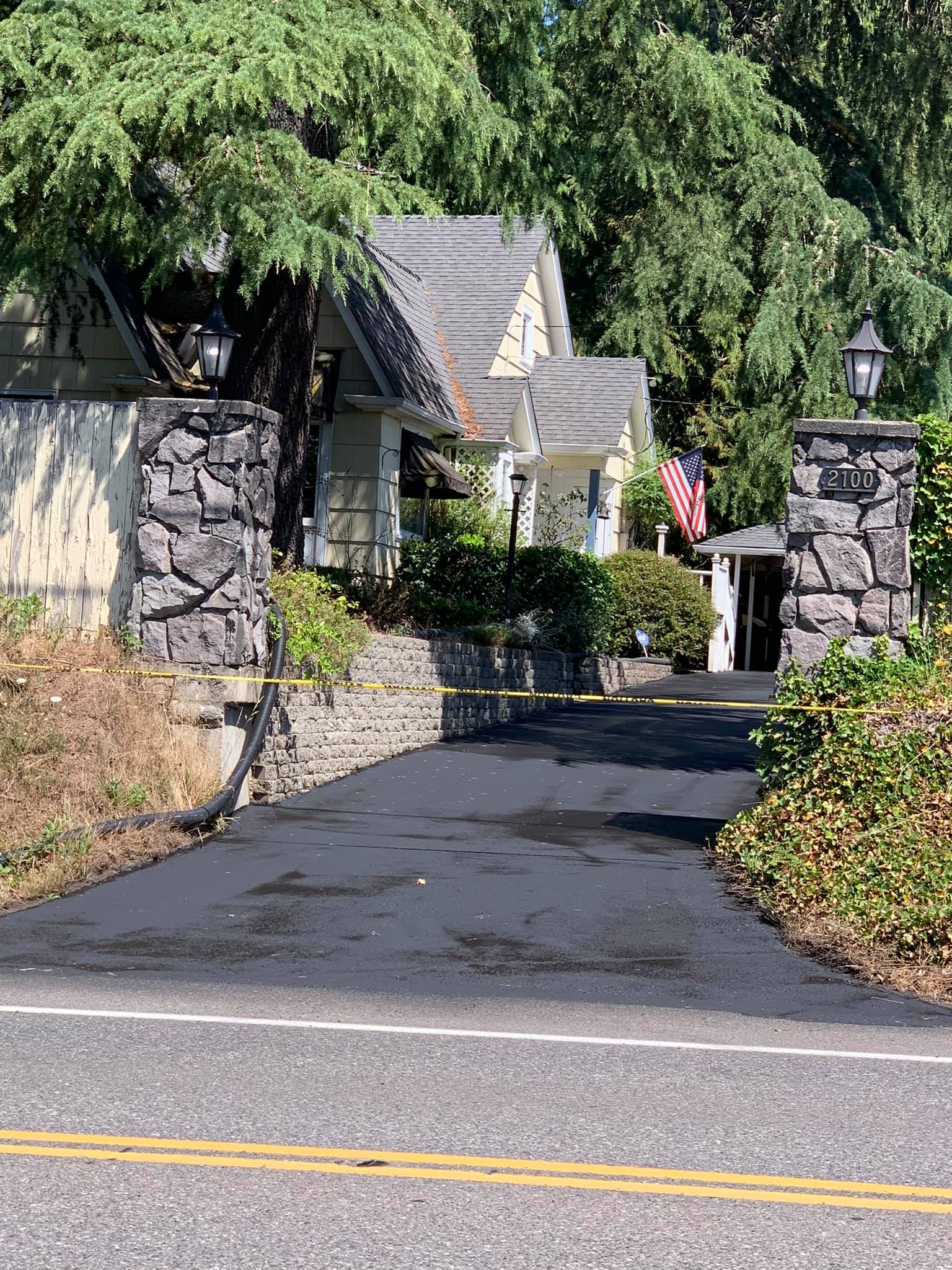 A driveway leading to a house with an american flag on the side of it.