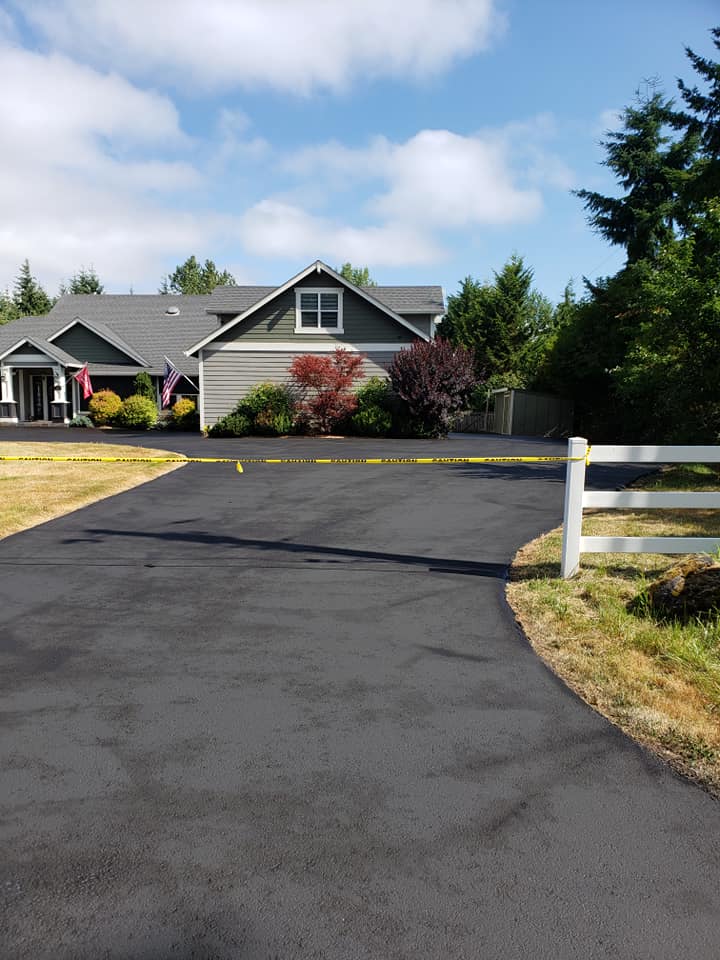 A driveway leading to a house with a white fence