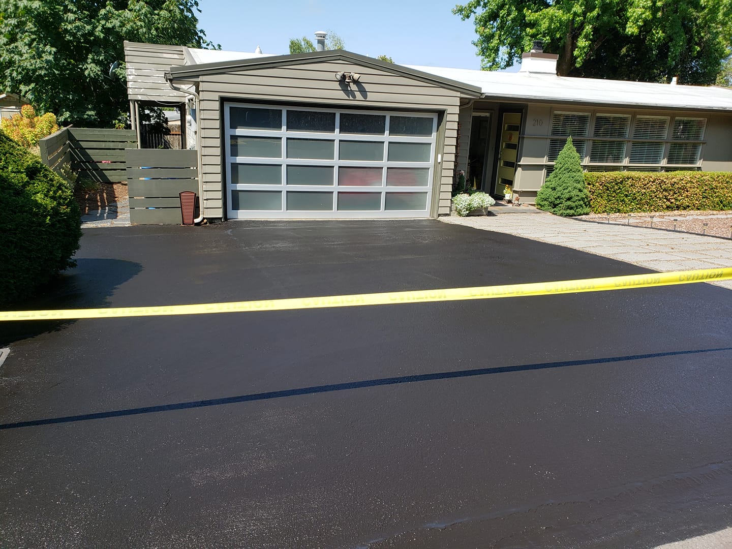 A house with a black driveway and a garage door