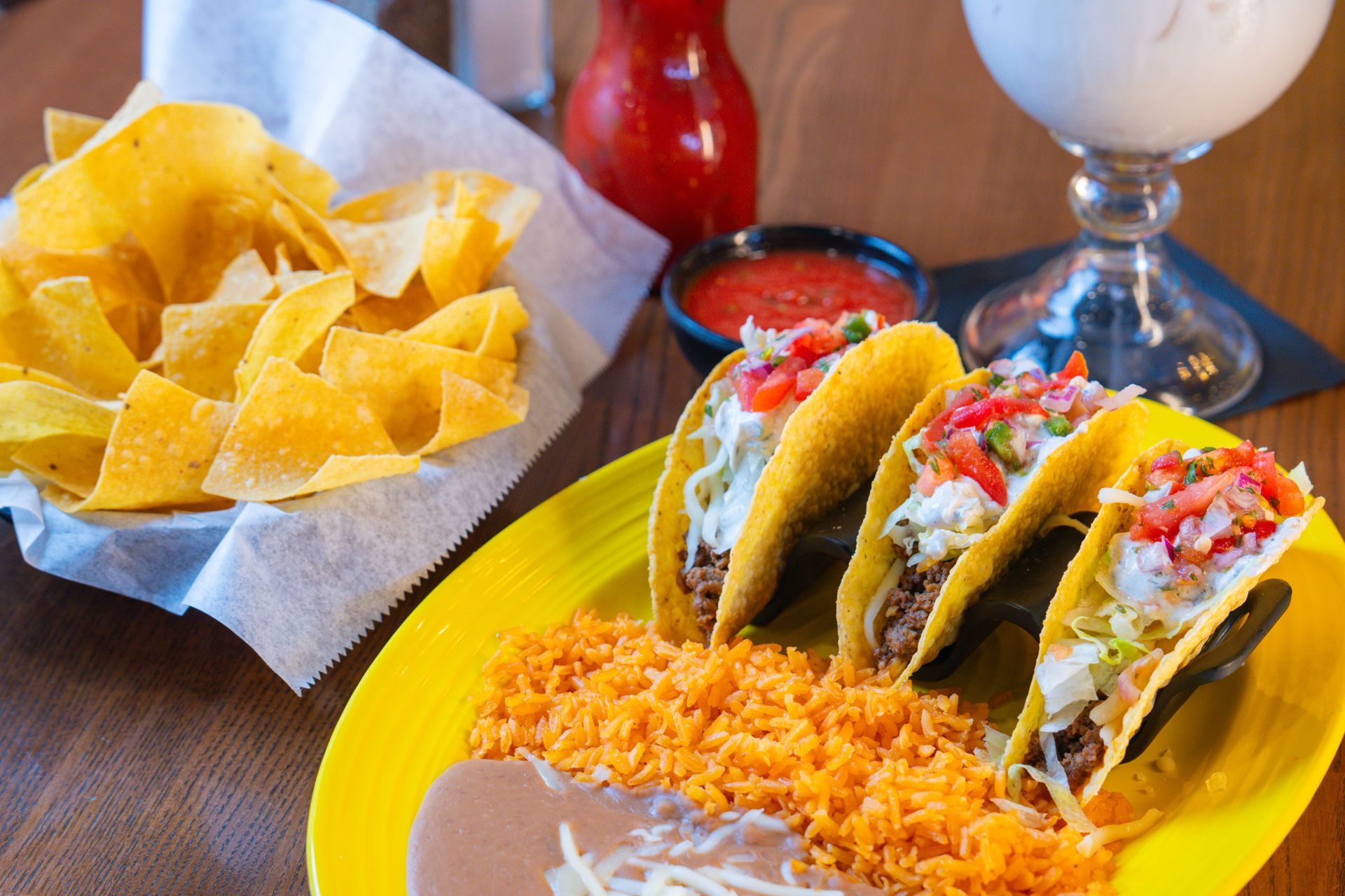 Friends raising glasses for a toast over a table filled with various colorful Mexican dishes, viewed from above.