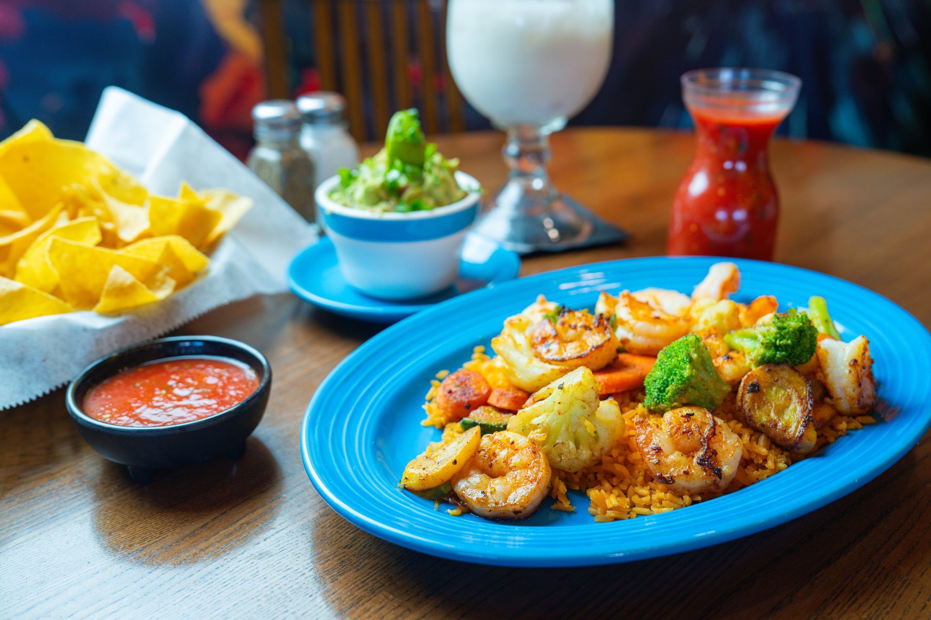 A cozy restaurant interior with wooden tables covered in colorful striped cloths and traditional wall tapestries.