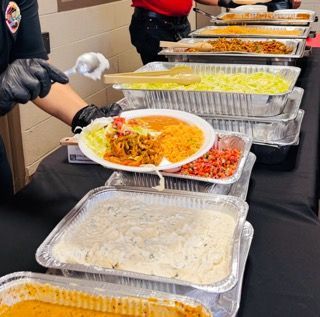 Five people at a wooden table in a brightly lit, rustic restaurant review menus together, smiling and collaborating.