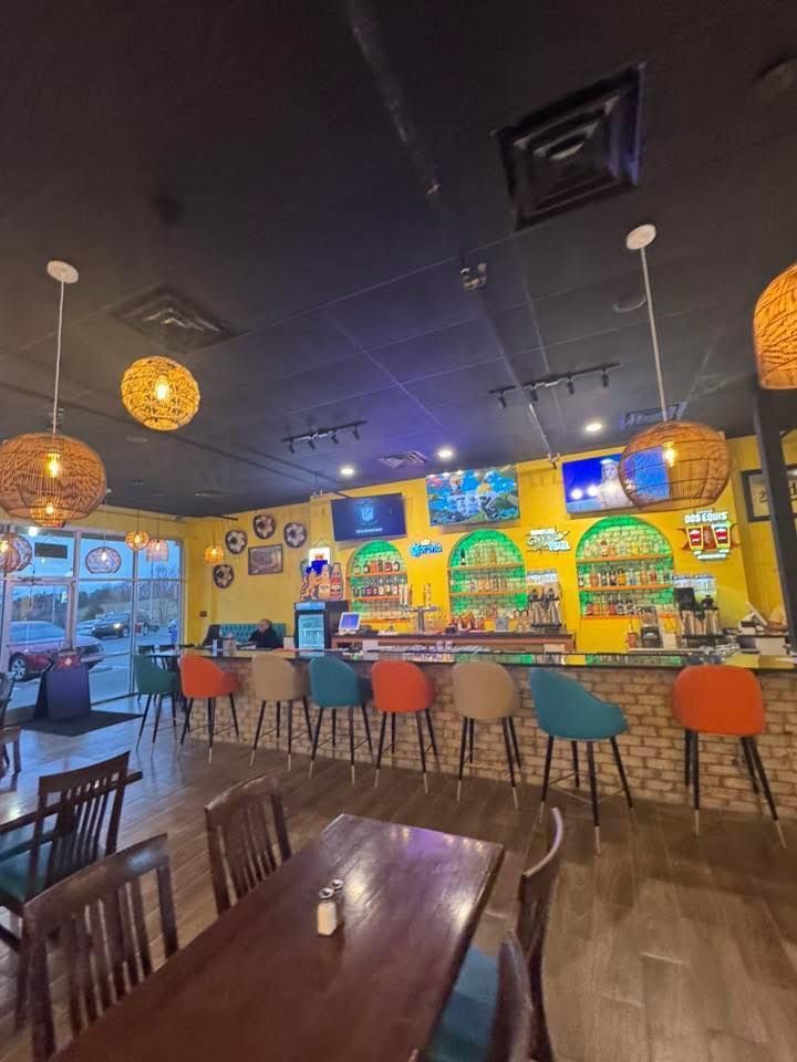 A tostada topped with shredded meat, lettuce, cheese, and sour cream on a white plate, with chips and salsa nearby.