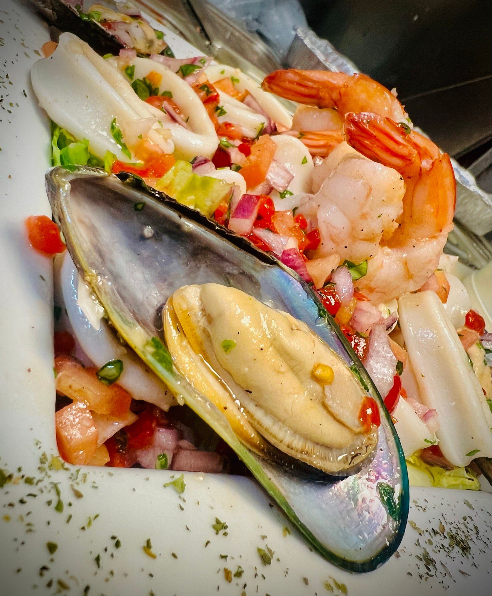 A white plate topped with seafood including mussels and shrimp