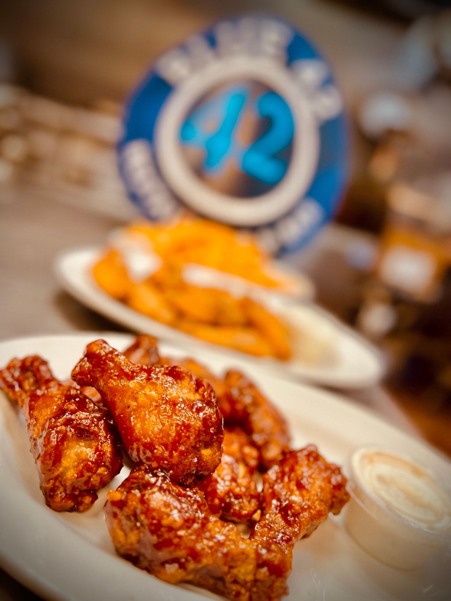 A plate of chicken wings with a dipping sauce on a table.