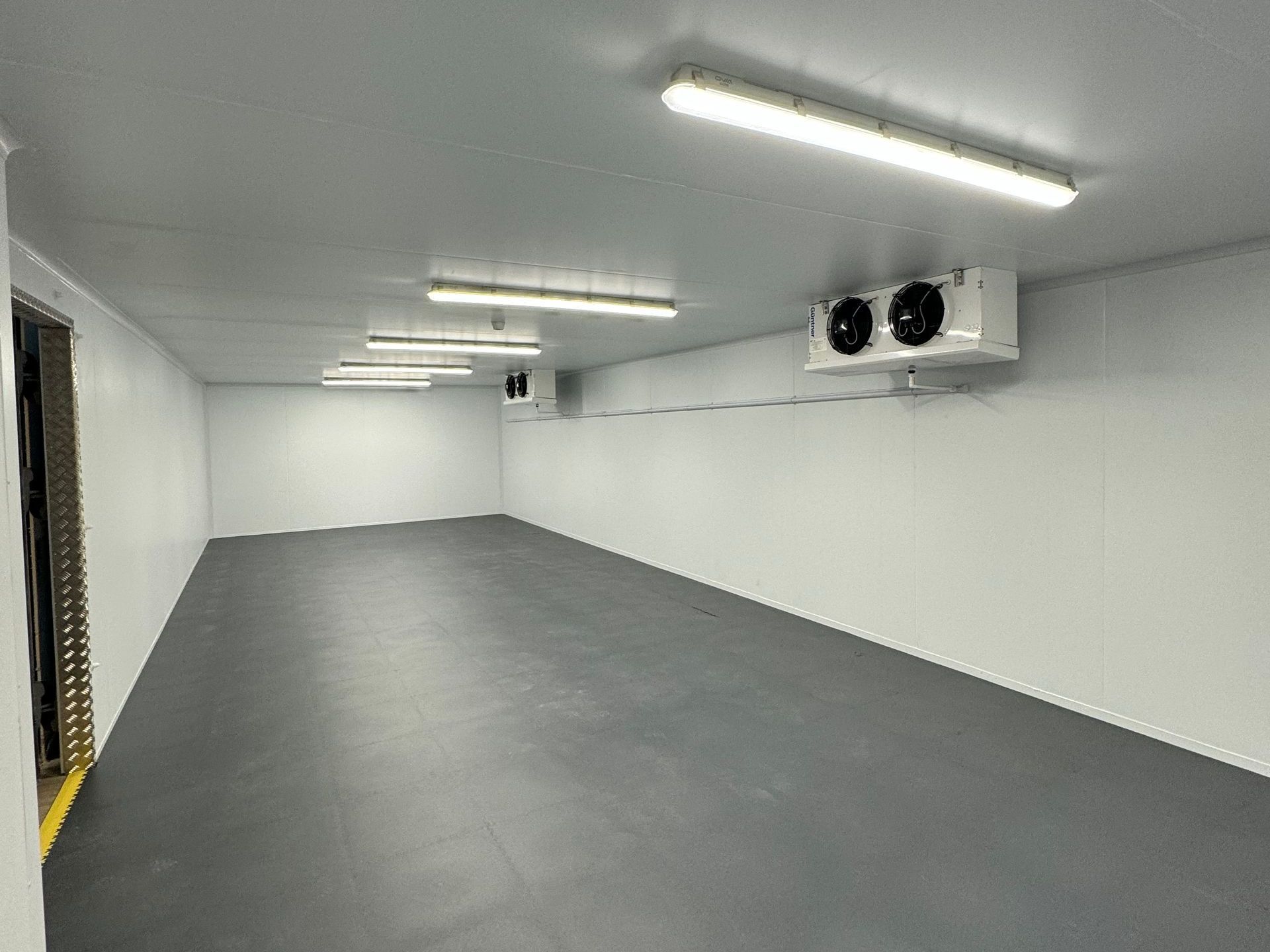 A room filled with stainless steel refrigerators and shelves.