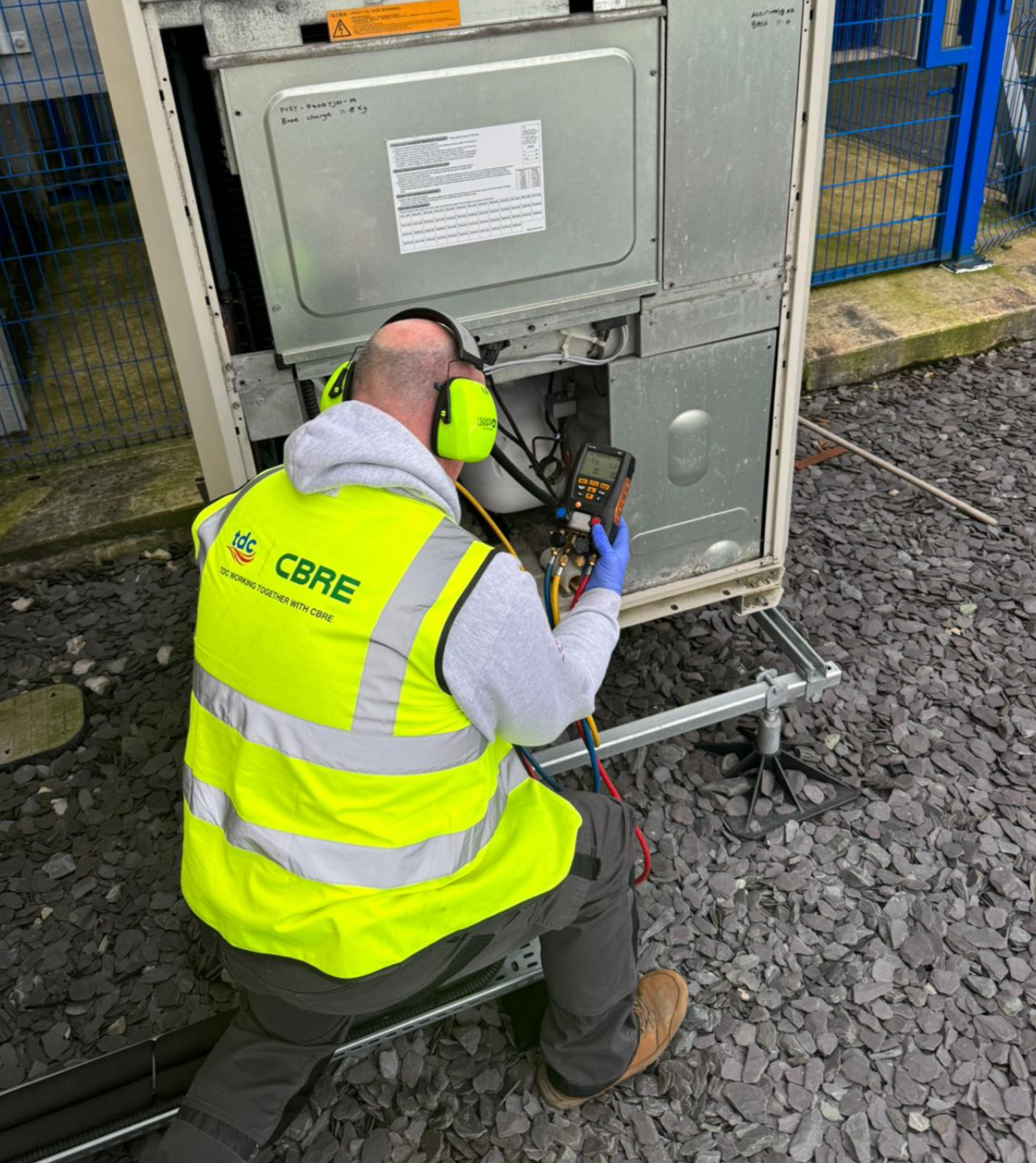 A man in a yellow vest is working on a machine.