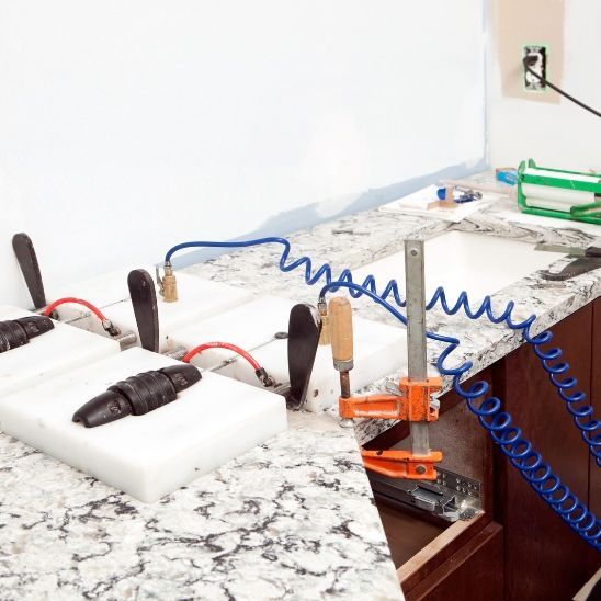 Professional countertop fabrication with clamps and adhesive on granite slabs. Granite countertop slabs being glued and clamped together during countertop fabrication.
