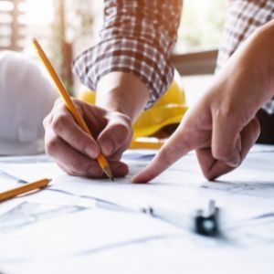 Collaborative planning on architectural drawings with pencil and hand gestures. Close-up of two hands working on architectural blueprints with a pencil and pointing finger, with sunlight in the background