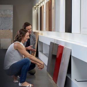 Customers reviewing material samples for kitchen or bathroom remodeling. Two people examining and discussing cabinet or countertop samples in a showroom.