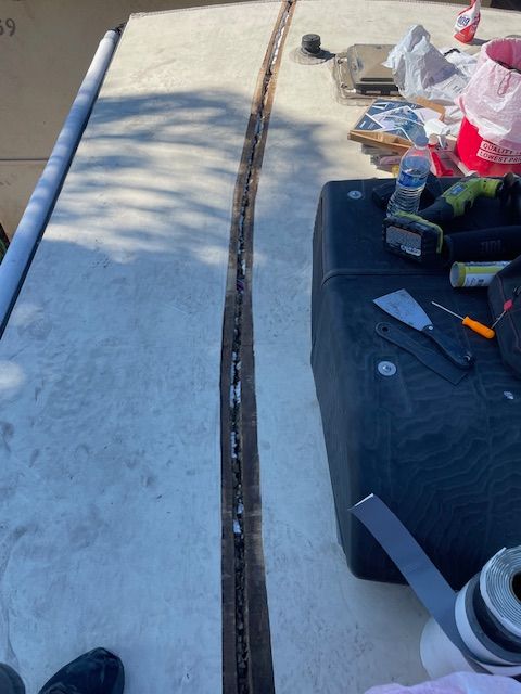 A person is working on a boat with tools on the deck