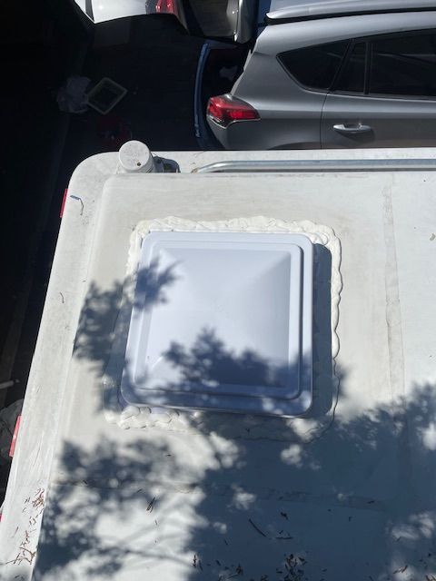 A white roof vent is sitting on top of a vehicle.