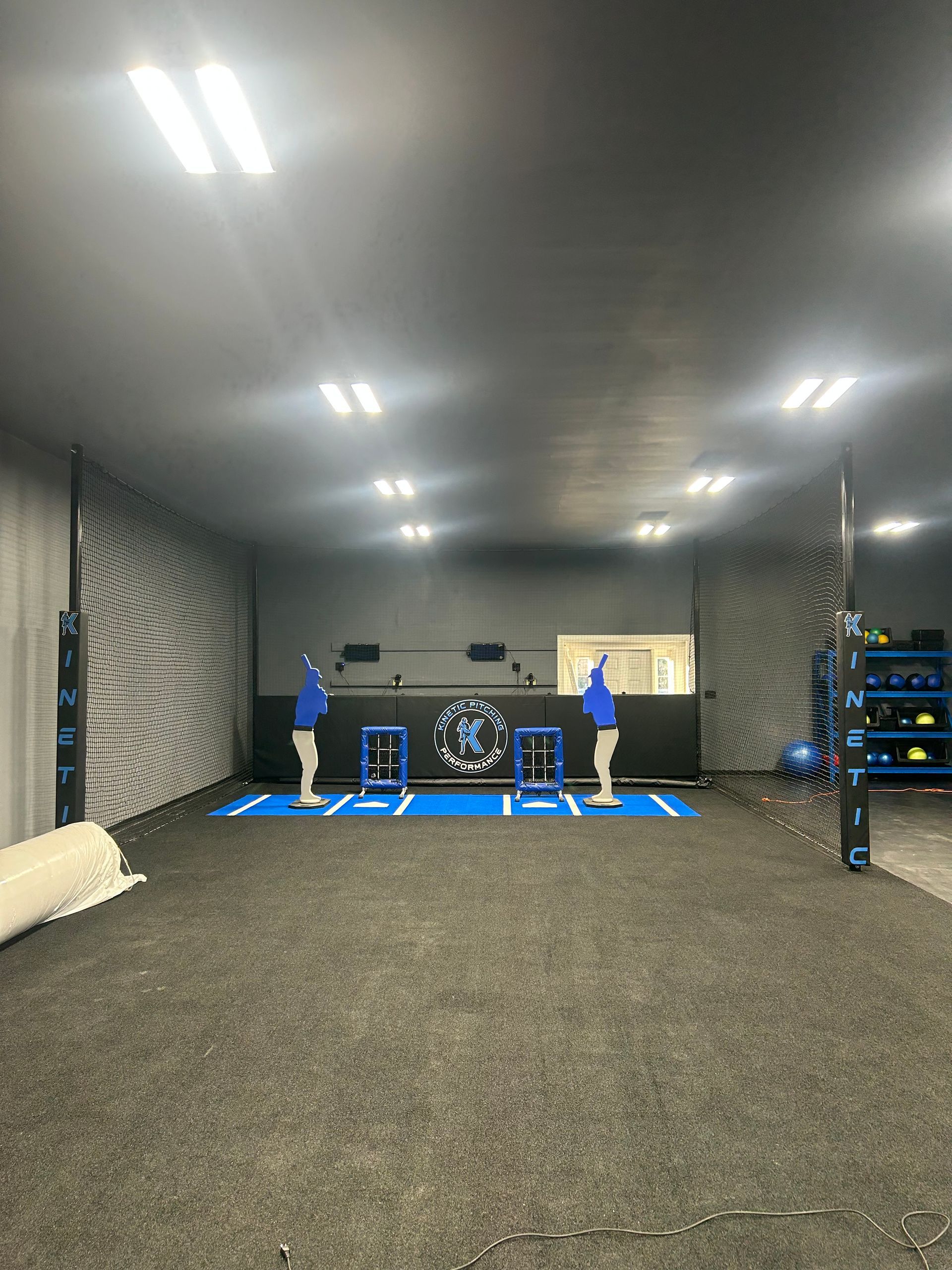 Two people in a gym, jumping on boxes. Blue and gray workout space with equipment.