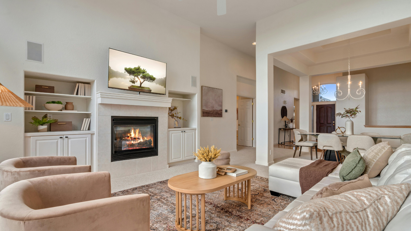 Living room with gray sofa, coffee table, woven lamps, plants, and decorative wall art.