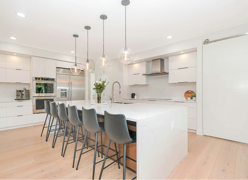 Modern white kitchen with island, pendant lights, and bar stools.
