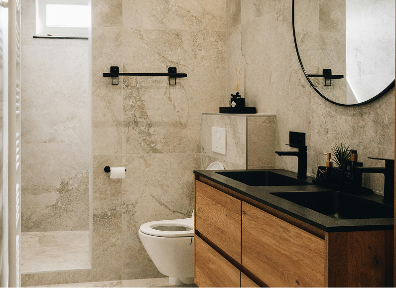 Modern bathroom with wooden vanity, black sinks and fixtures, and neutral tiled walls.