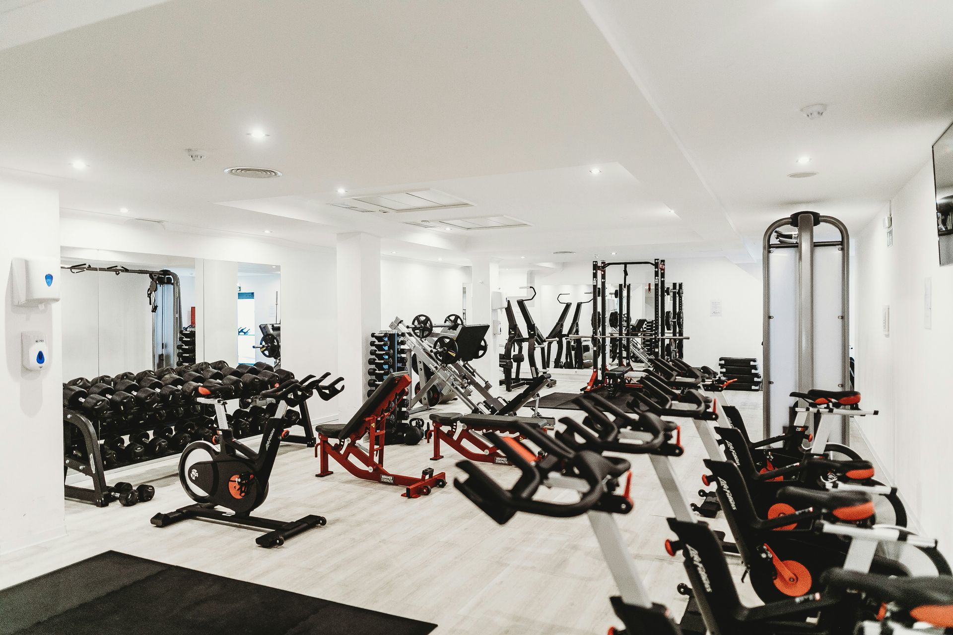 Gym interior with weights, exercise bikes, and weight machines in a bright, modern space.