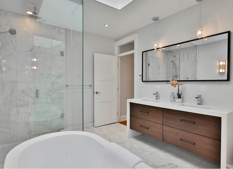 Modern bathroom with wooden vanity, black sinks, and large round mirror.