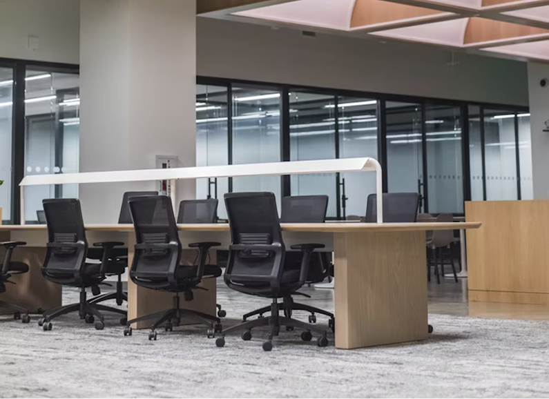 Modern white kitchen with island, gray stools, pendant lights, stainless steel appliances, and wood floors.