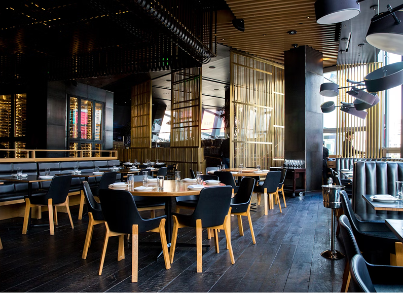 Cozy living room with grey sofa, round coffee table, wicker lamps, and plants.