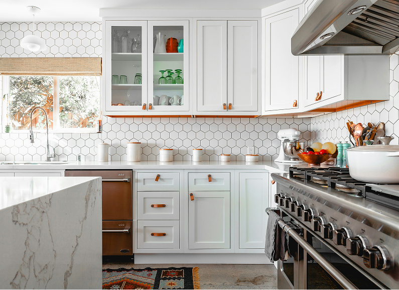 Modern white kitchen with island, stools, stainless steel appliances, and pendant lights.
