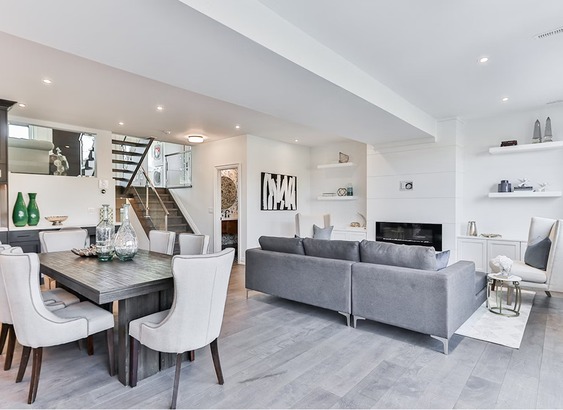 Living room with gray sofa, coffee table, woven lamps, plants, and decorative wall art.