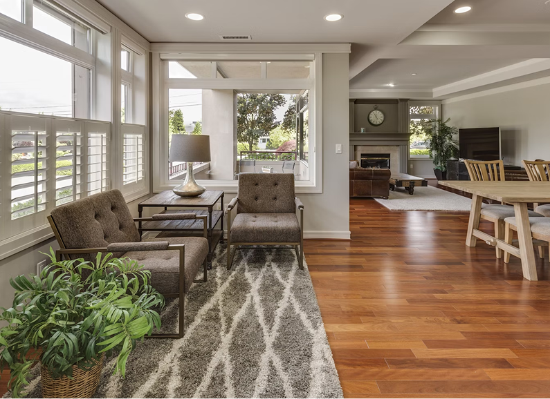 Cozy living room with grey sofa, round coffee table, wicker lamps, and plants.