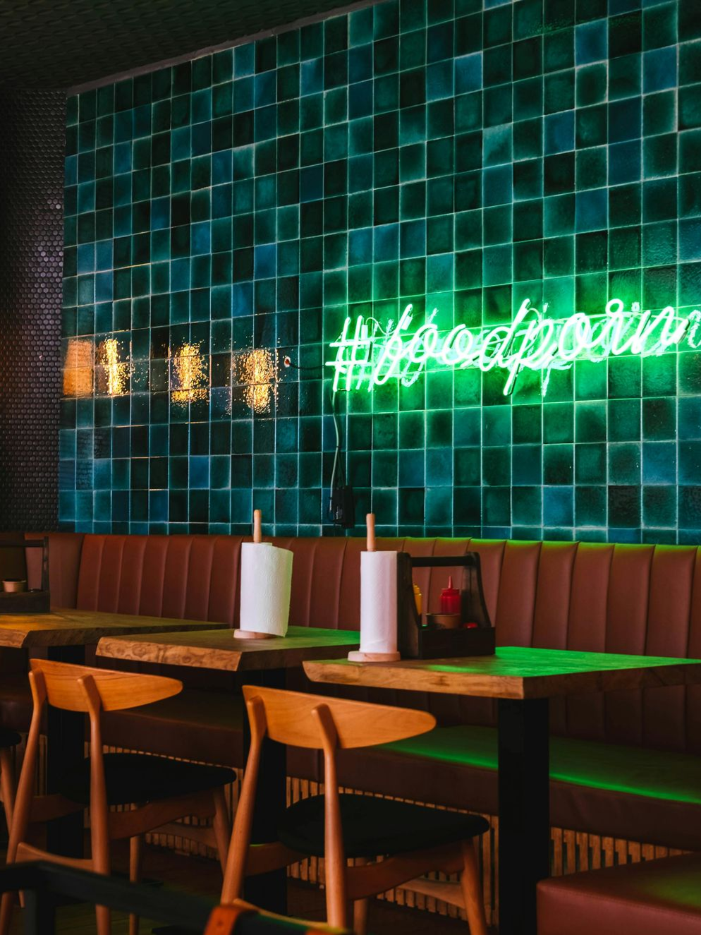 Modern white kitchen with island, gray stools, pendant lights, stainless steel appliances, and wood floors.
