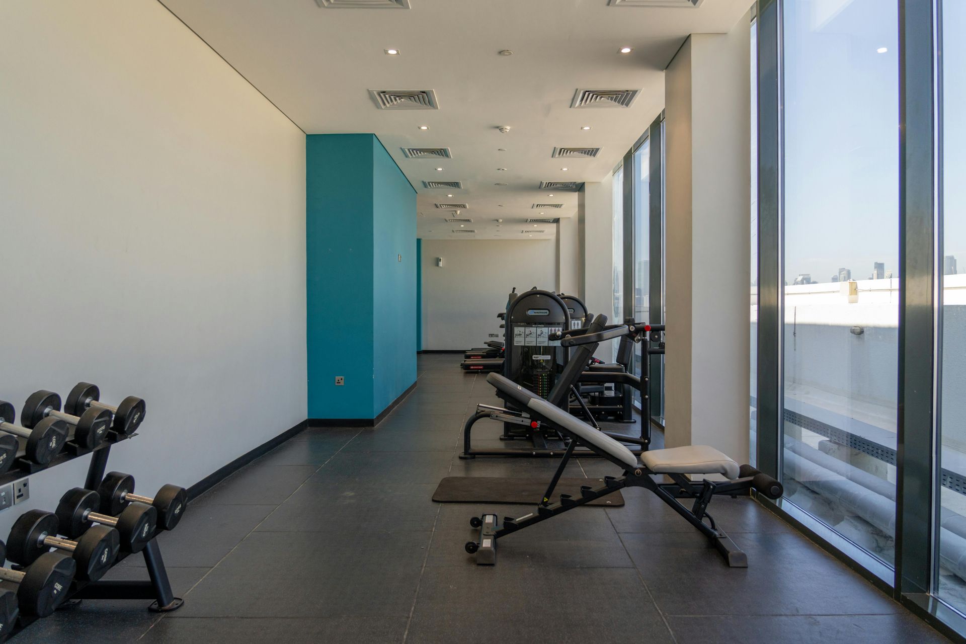Modern bathroom with wooden vanity, black sinks/fixtures, toilet, and light stone tile walls.