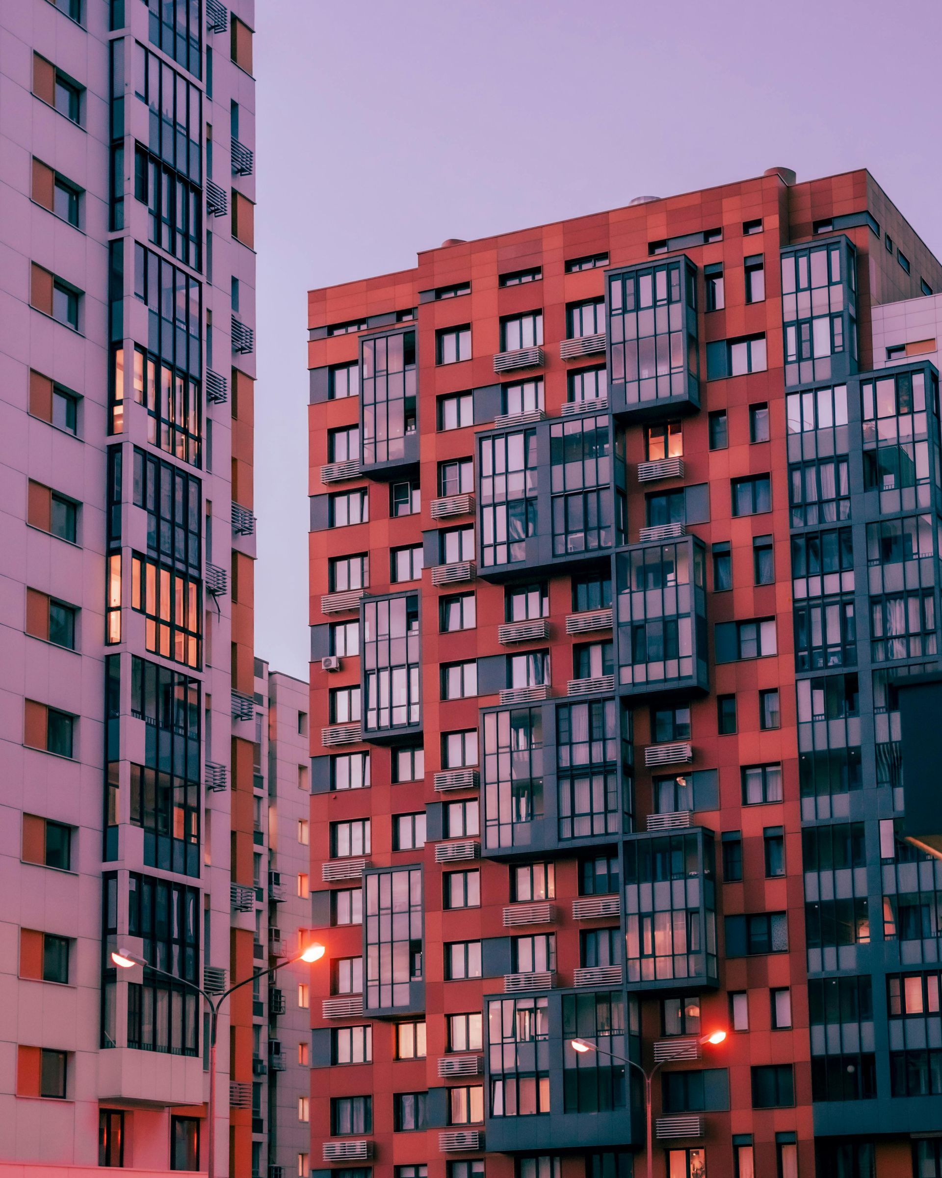 Meeting room with large windows, wooden table, pink chairs, and modern lighting.
