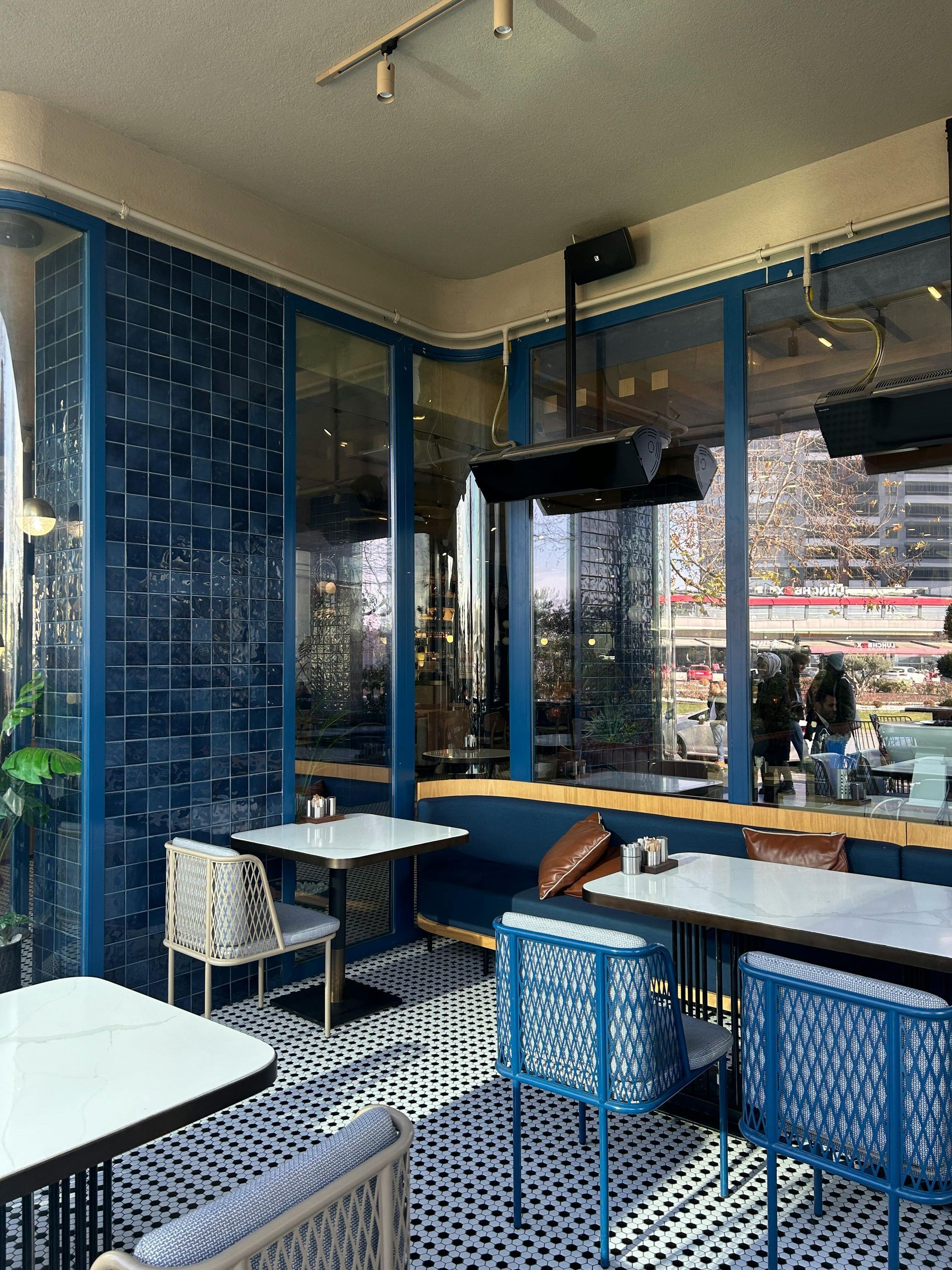 Restaurant interior with tables set for dining; dark walls, artwork, dim lighting.