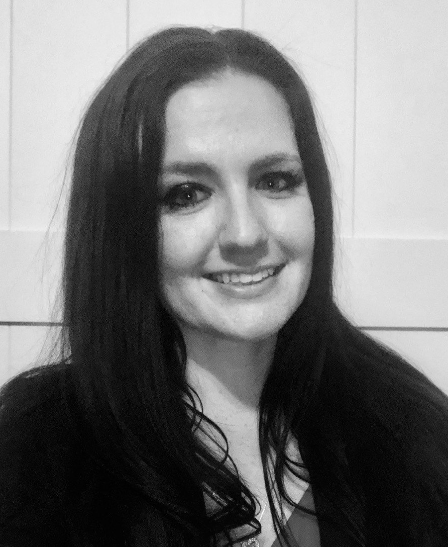 GABBIE CAUDILL with long dark hair is smiling in a black and white photo .