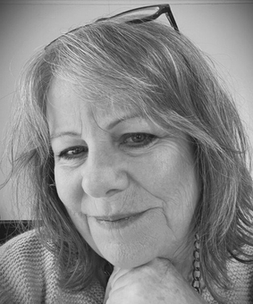 an older woman wearing glasses and a sweater is smiling in a black and white photo .