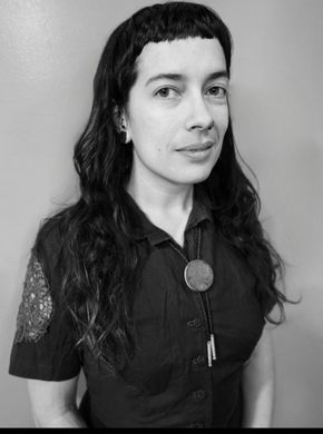 AJ Schott (she/her) smiling in a black and white photo .