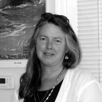 an older woman wearing glasses and a sweater is smiling in a black and white photo .