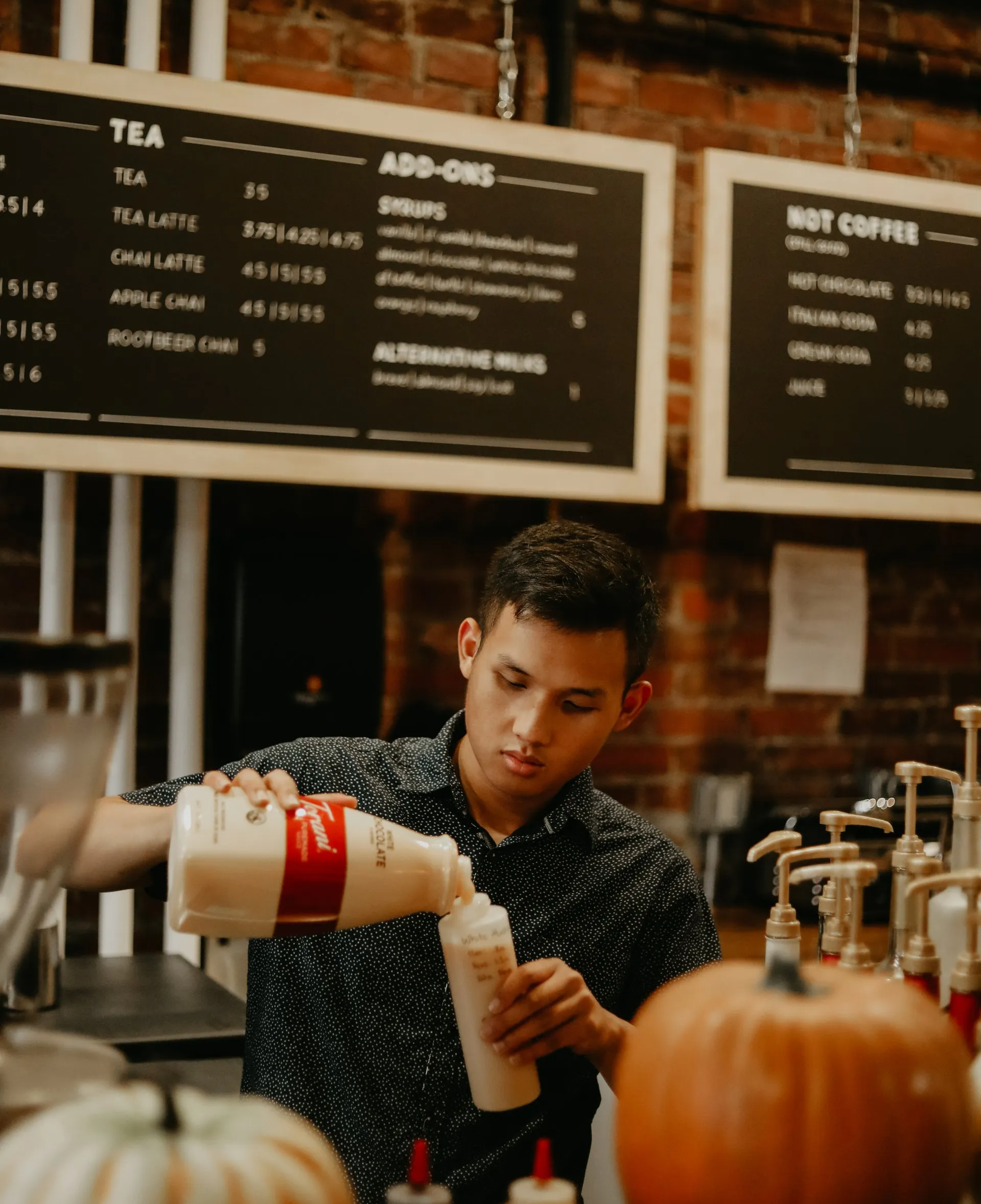 a man is pouring milk into a cup at a coffee shop