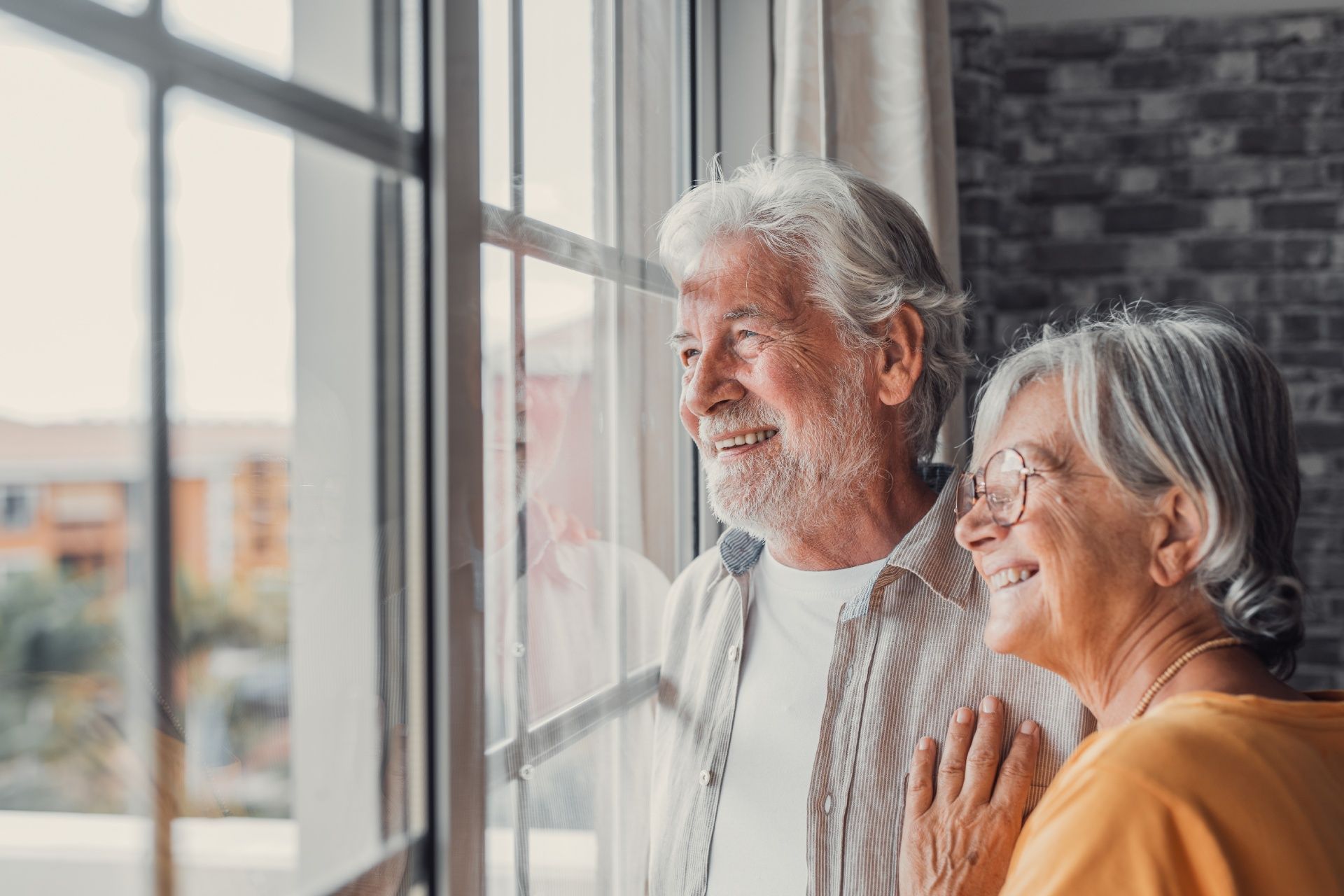 An Elderly Couple Is Looking out Of a Window.