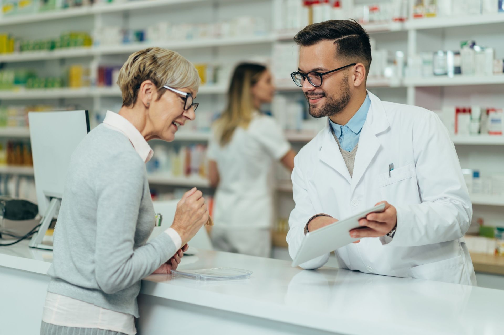 A pharmacist is talking to a woman in a pharmacy.