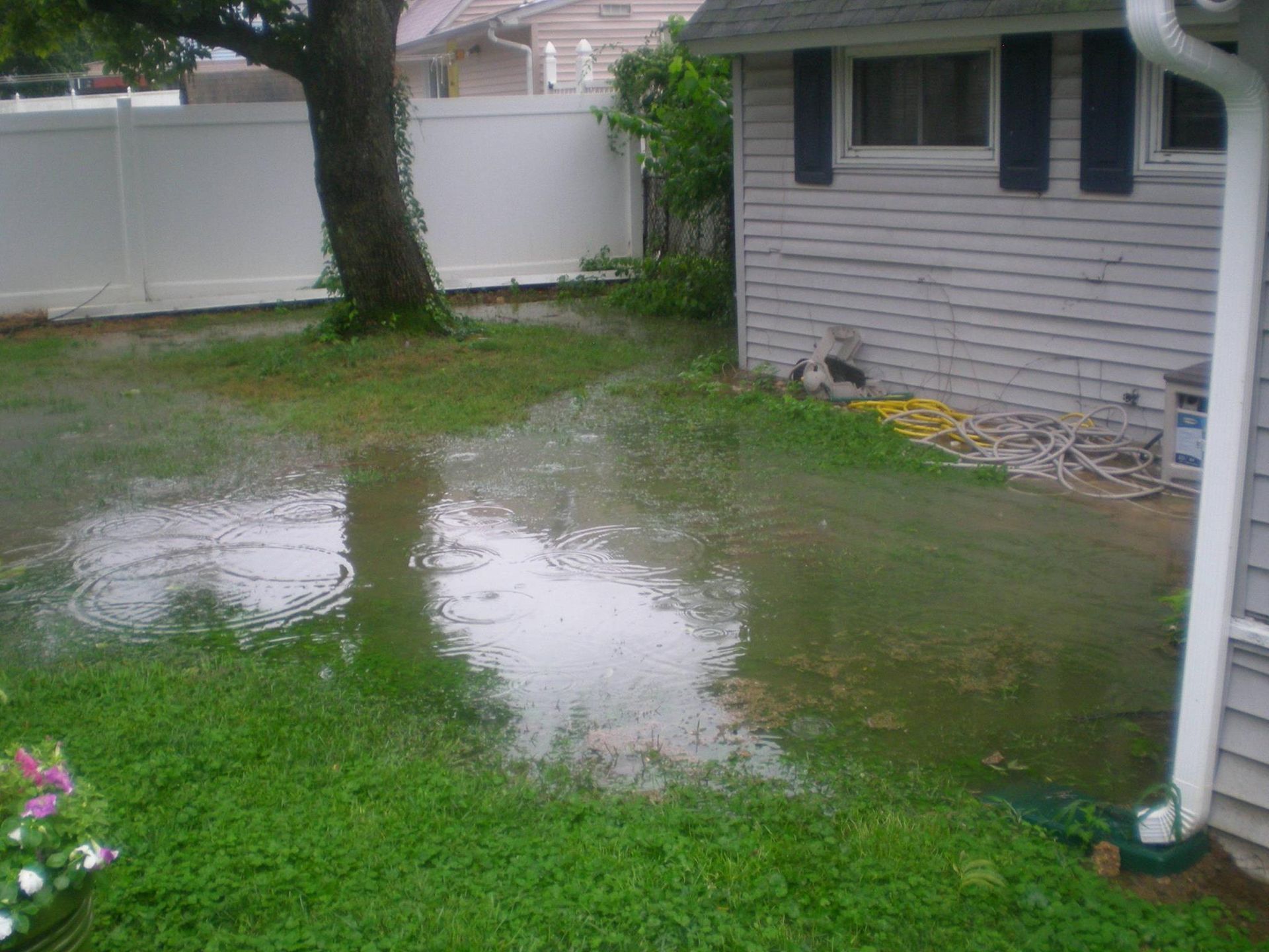 A flooded yard with a white house in the background
