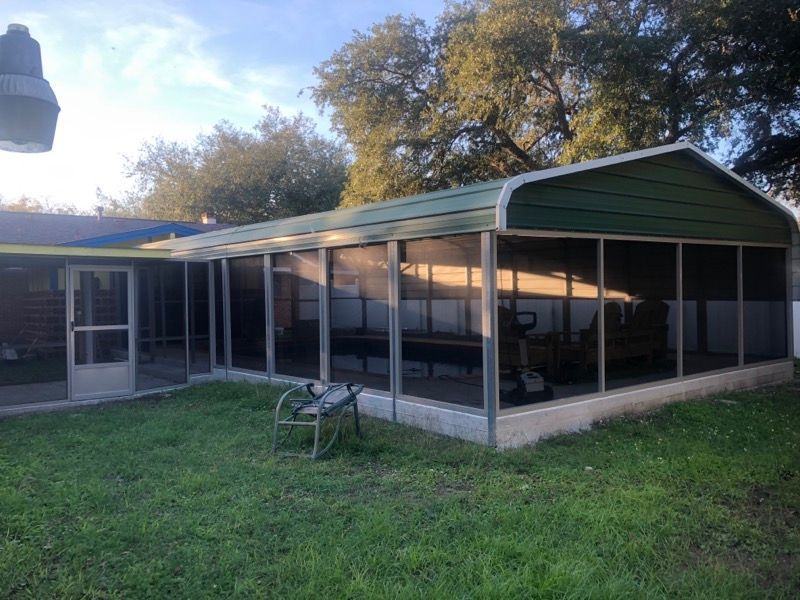 A screened in porch in the backyard of a house.