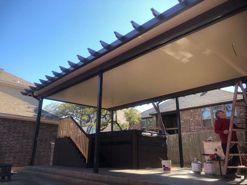 A man is standing on a ladder under a covered porch