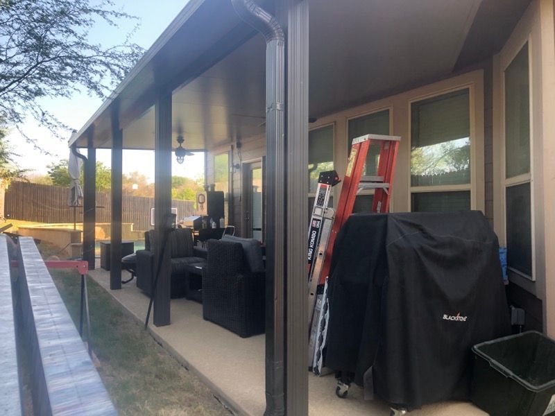 A patio with a ladder and a grill on it.