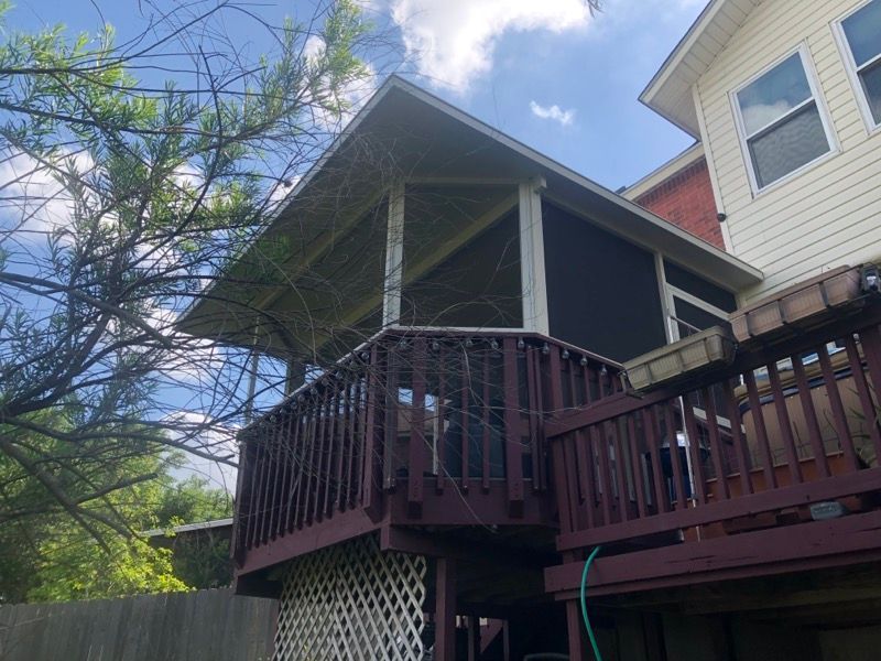 There is a screened in porch on the back of a house.