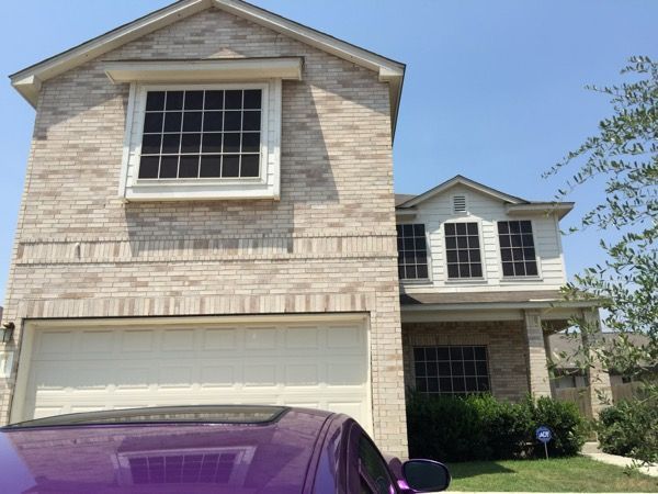 A purple car is parked in front of a brick house