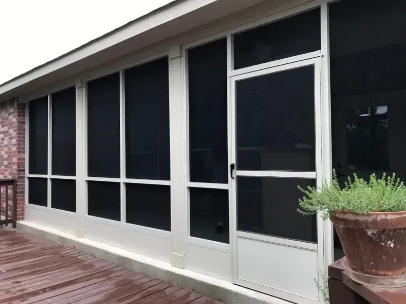 A screened in porch with a potted plant in front of it