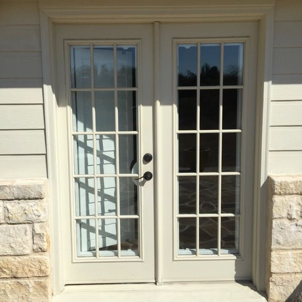 A white french door with a brick wall behind it